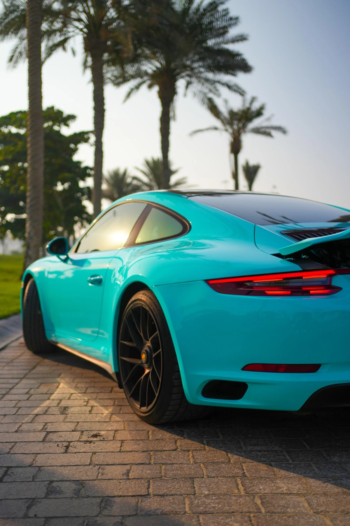 Turquoise Porsche 911 on a palm-lined UAE street